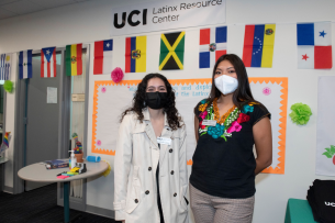 Two students wear masks in front of the UCI Latinx Resource Center.